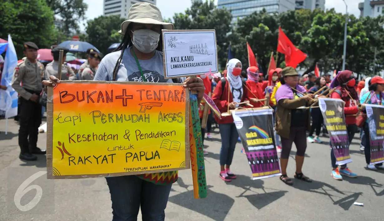 Seorang massa membawa poster saat aksi long march menuju Istana Presiden, Jakarta, Selasa (8/3). Aksi memperingati Hari Perempuan Internasional ini menuntut pemerintah memberikan perlindungan terhadap perempuan Indonesia. (Liputan6.com/Gempur M Surya)
