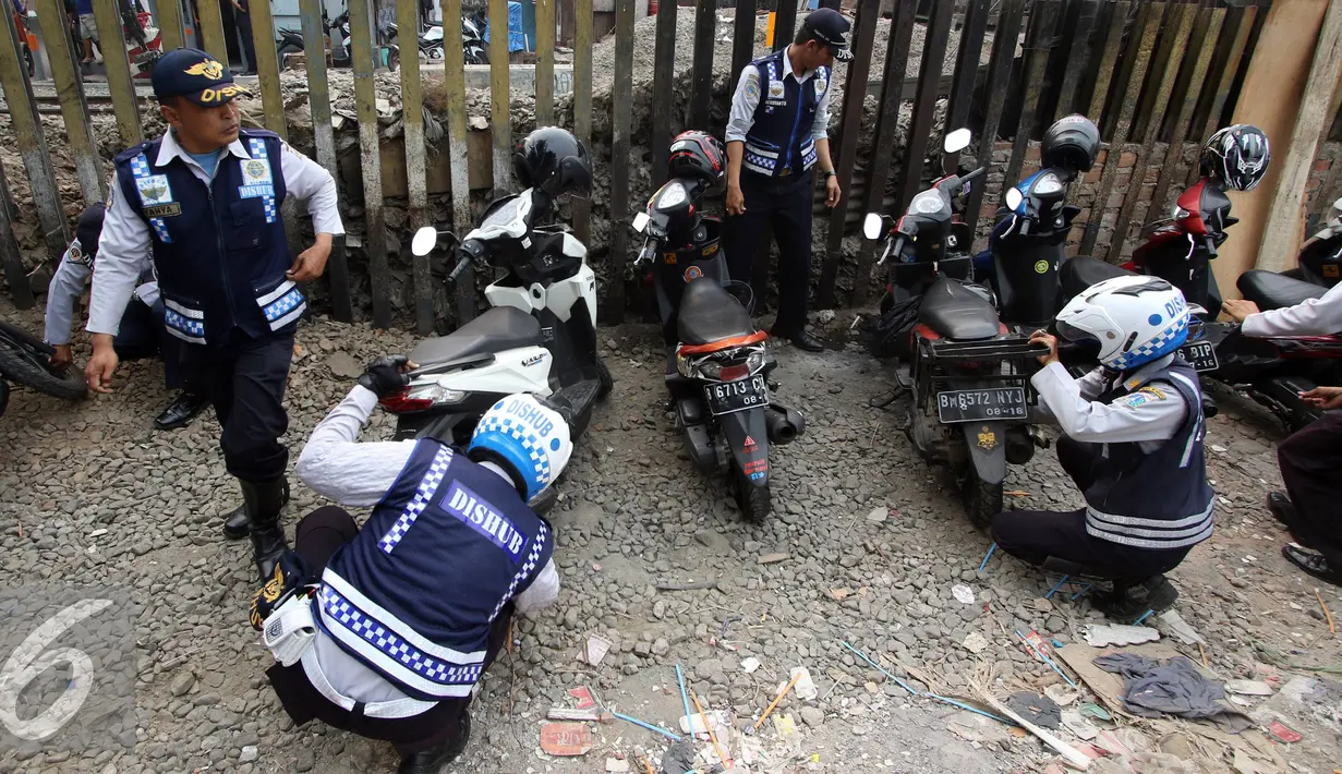 Petugas Dishub mencabut pentil kendaraan roda dua dalam operasi penertiban parkir liar di Pusat, Jumat (23/10/2015). Meskipun informasi penertiban diduga telah bocor, ratusan kendaraan yang parkir liar tetap ditertibkan. (Liputan6.com/Immanuel Antonius)