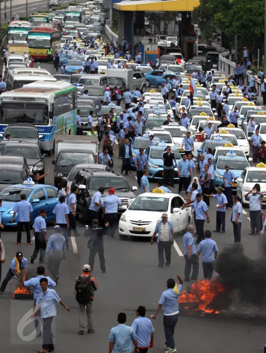 Para sopir taksi yang melakukan demo membakar ban dan juga memblokir jalan tol dalam kota, Mampang, Jakarta, Selasa (22/3). Terlihat asap membumbung tinggi dari ban yang terbakar sebagai wujud aksi anarkis sopir taksi. (Liputan6.com/Johan Tallo)