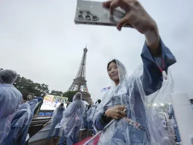 Asom Kim, fisioterapis dari tim Korea Selatan berfoto selfie dengan latar belakang Menara Eiffel dari atas kapal menyusuri Sungai Seine saat upacara pembukaan Olimpiade Paris 2024, Jumat (26/7/2024). (AP Photo/Lee Jin-man, Pool)