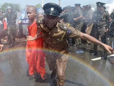 Seorang polisi mengamankan biksu saat aksi protes di kota pelabuhan selatan Hambantota, Sri Lanka (7/1). Mereka memprotes pembuatan zona industri untuk investasi China di sebuah kawasan di Sri Lanka. (AFP/ Ishara S. Kodikara)