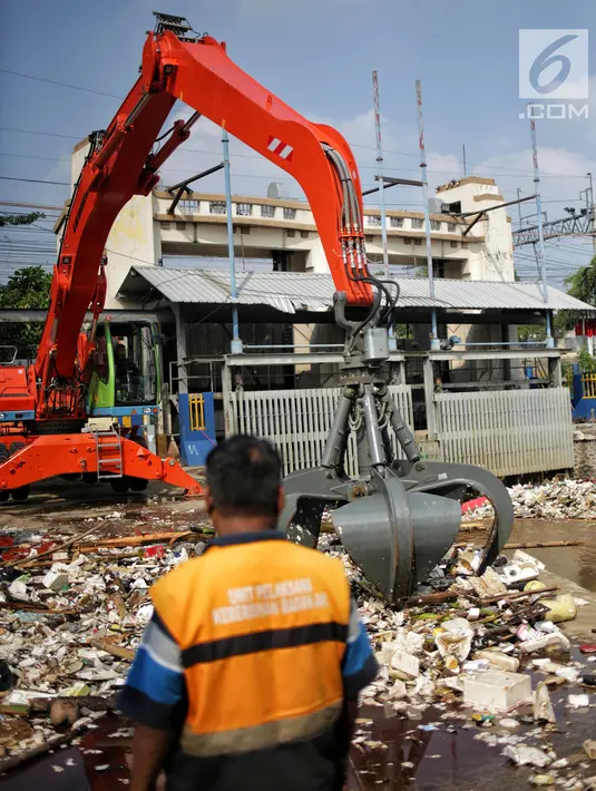 Petugas kebersihan mengeruk sampah menggunakan alat berat di Pintu Air Manggarai, Jakarta, Selasa (26/2). Meningkatnya debit air Sungai Ciliwung menyebabkan terjadi penumpukan sampah di Pintu Air Manggarai. (Liputan6.com/Faizal Fanani)