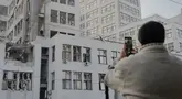 Seseorang mengambil foto gedung Derzhprom—sebuah gedung pencakar langit bersejarah Soviet—yang rusak setelah serangan rudal di Kharkiv pada 29 Oktober 2024. (Ivan SAMOILOV/AFP)