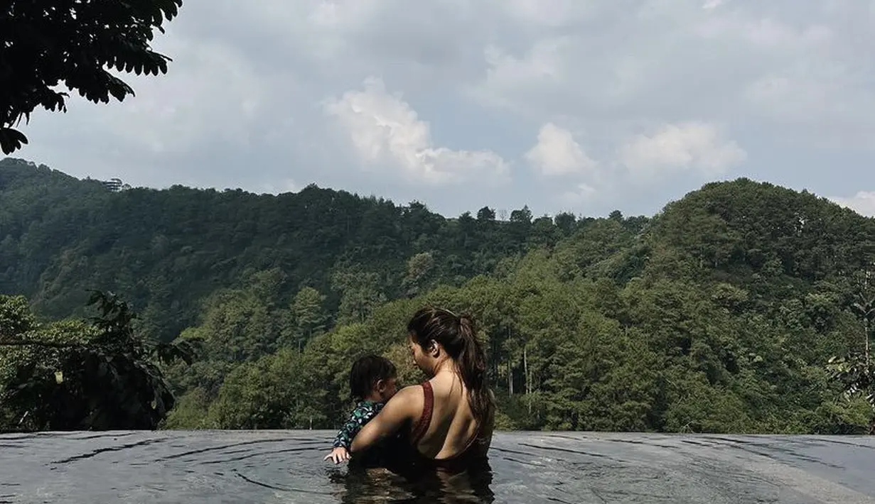 Bersama Baby Izz tampak Nikita Willy mengajaknya berenang dengan pemandangan yang indah. Terlihat, Nikita mengenakan baju renang backless warna maroon. [Instagram/ @nikitawillyofficial94]