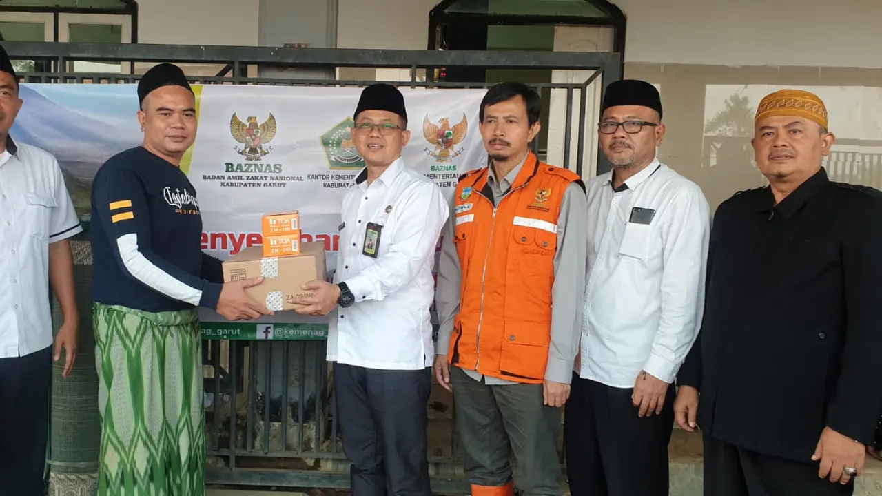 Kepala Kemenag Garut Cece Hidayat, bersama Ketua Baznas Garut Abdullah Effendy, secara simbolis memberikan fasilitas amplifier toa yang diberikan kepada pengurus masjid At-Thohirin di kawasan blok terdampak banjir Cimacan. (Liputan6.com/Jayadi Supriadin)