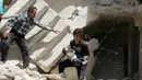 Relawan saat mengevakuasi bayi dari sebuah bangunan runtuh setelah serangan udara di wilayah yang dikuasai pemberontak al-Kalasa di kota Suriah bagian utara, Aleppo, Kamis (28/4). (AFP PHOTO / Ameer ALHALBI)