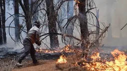 Ratusan petugas pemadam kebakaran berjibaku mengendalikan kebakaran besar menghanguskan sekitar 12.000 hektare hutan. Tampak dalam foto, seorang warga setempat berusaha memadamkan api saat terjadi kebakaran hutan di Epuyen, Patagonia, Argentina, Minggu 11 Januari 2026. (AP Photo/Nicolas Palacios)