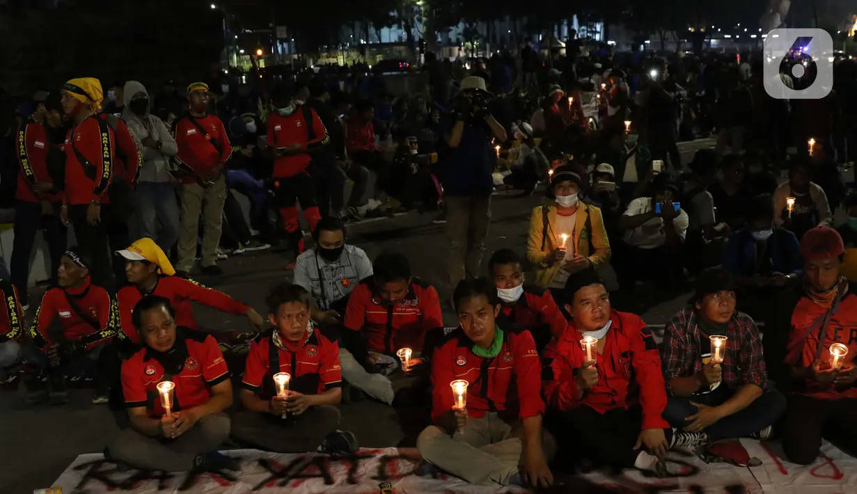 Beberapa peserta aksi unjuk rasa memegang lilin saat doa bersama lintas agama di Kawasan Patung Kuda, Jakarta, Selasa (10/11/2020). Sejumlah massa gabungan dari berbagai organisasi buruh dan mahasiswa berunjuk rasa menolak pengesahan Omnibus Law UU Cipta Kerja. (Liputan6.com/Helmi Fithriansyah)