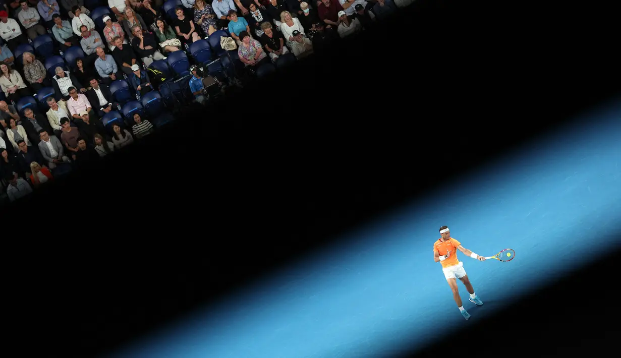Petenis Spanyol, Rafael Nadal mengembalikan bola ke arah petenis Amerika Serikat, Mackenzie McDonald saat laga putaran kedua Australian Open 2023 di Melbourne, Australia, Rabu (18/01/2023). (AFP/Martin Keep)