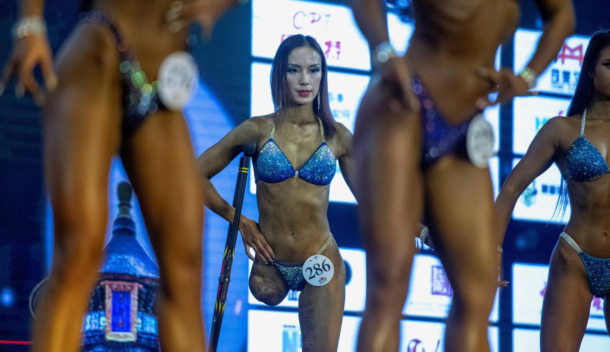 Atlet Binaraga asal China, Gui Yuna (tengah) saat berada dipanggung dalam ajang International Weightlifting Federation (IWF) Beijing 2020 di Beijing, China, Jumat (11/12/2020). (AFP/NOEL CELIS)