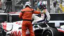 Pembalap Tim Haas, Mick Schumacher dibantu oleh marshall keluar dari mobilnya usai mengalami kecelakaan saat Formula 1 GP Monako yang berlangsung di Circuit de Monaco, Minggu, 29 Mei 2022. (AFP/Loic Venance)