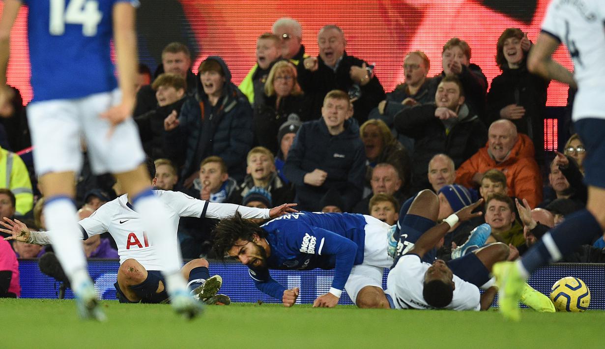 Gelandang Everton, Andre Gomes, terjatuh usai dilanggar oleh penyerang Tottenham Hotspur, Son Heung-min, pada laga Premier League di Goodison Park, Minggu (3/11). Tekel tersebut menyebabkan Gomes mengalami patah kaki. (AFP/Oli Scarff)