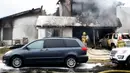 Petugas pemadam kebakaran menyemprotkan air di lokasi kecelakaan pesawat di sebuah rumah di Yorba Linda, California (3/2). Hingga kini penyebab kecelakaan masih diselidiki. (AP Photo/Alex Gallardo)