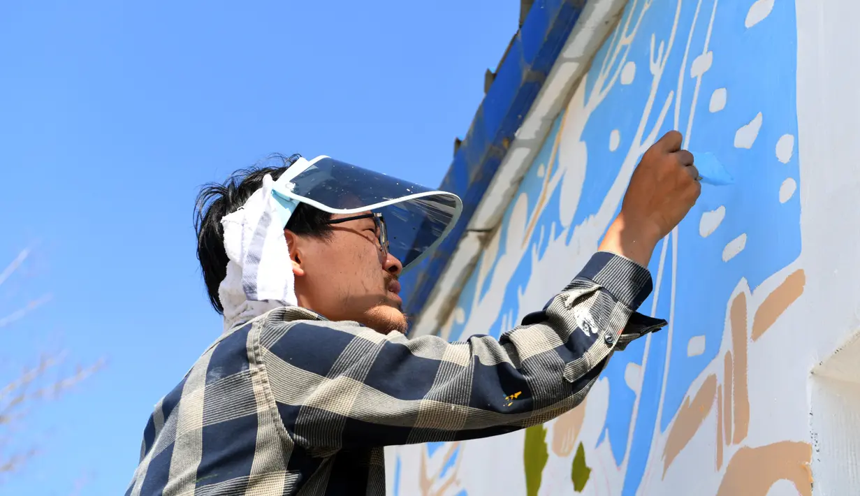 Seorang mahasiswa dari Universitas Seni Jilin melukis di tembok sebuah rumah di Desa Qingshui, Kota Changchun, China timur laut (18/6/2020). Para mahasiswa dan pengajar dari Universitas Seni Jilin menghiasi desa tersebut dengan mural. (Xinhua/Lin Hong)