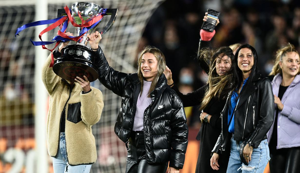 Pemain Barcelona, Alexia Putellas (tengah) merayakan kemenangan bersama rekannya sambil mengangkat trofi Liga Spanyol di Camp Nou, Barcelona 13 Maret 2022. (AFP/Josep Lago)