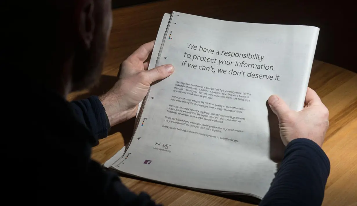 Seorang pria membaca iklan berisi permintaan maaf di sebuah surat kabar Inggris, 25 Maret 2018. CEO Facebook Mark Zuckerberg meminta maaf terhadap skandal Cambridge Analytica menggunakan iklan di sembilan surat kabar Inggris dan AS. (Oli SCARFF/AFP)