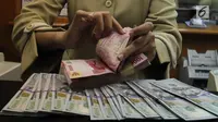 Teller tengah menghitung mata uang rupiah di penukaran uang di Jakarta, Junat (23/11). Nilai tukar dolar AS terpantau terus melemah terhadap rupiah hingga ke level Rp 14.504. (Liputan6.com/Angga Yuniar)