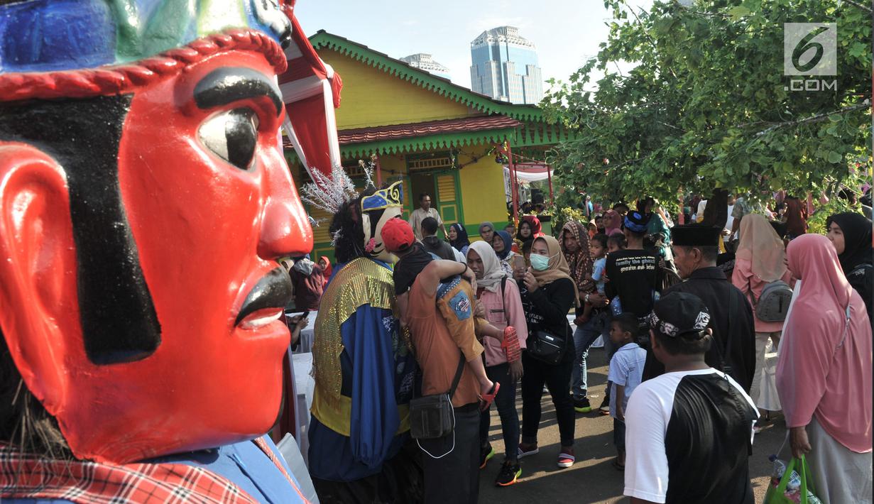 Warga berfoto di dekat ondel-ondel saat Lebaran Betawi di Monas, Jakarta, Minggu (21/7/2019).Untuk pertama kalinya Lebaran Betawi digelar di Monas yang diisi oleh beragam seni dan budaya masyarakat Betawi dalam rangka memeriahkan HUT DKI Jakarta. (merdeka.com/Iqbal S. Nugroho)