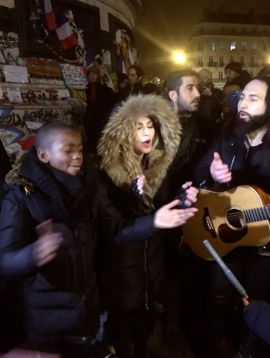 Aksi Madonna dan putranya David Banda yang diiringi gitaris Monte Pittman menggelar konser jalanan di Place de la Republique, dekat tempat peringatan para korban serangan 13 November Paris yang menewaskan 130 orang, Kamis (10/12/2015). (JULES MAHE/AFP)