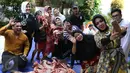 Syahrini berselfie dengan warga yang membantunya menyiapkan daging kurban di kawasan Bogor, Jawa Barat, Senin (12/9). Syahrini berharap saat Idul Adha tahun depan bisa berkurban lebih dari 3 sapi. (Liputan6.com/Herman Zakharia)