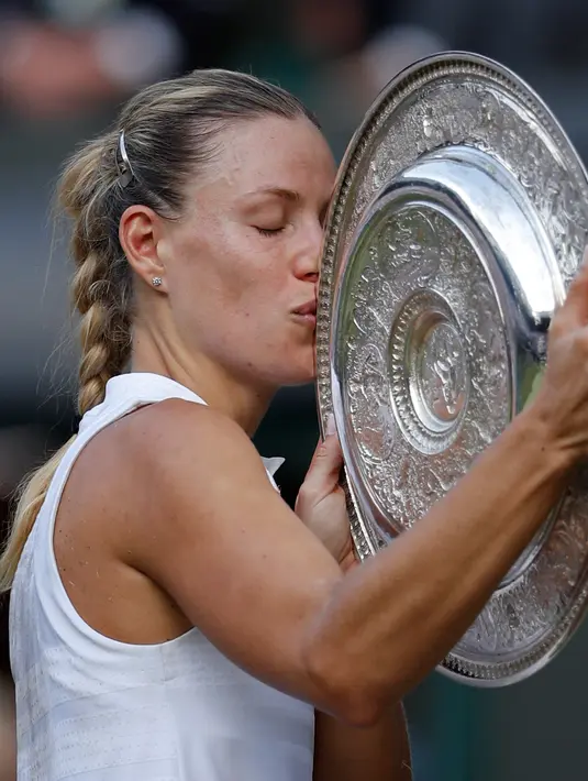 Petenis Jerman, Angelique Kerber mencium trofi usai mengalahkan petenis AS, Serena Williams pada final tunggal putri kejuaraan Tenis Wimbledon 2018 di London, (14/7). Kerber menang atas Williams 6-3,6-3. (AP Photo/Andrew Couldridge)