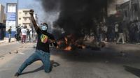Seorang pendukung oposisi bereaksi di depan barikade yang terbakar selama demonstrasi yang diserukan oleh partai-partai oposisi di Dakar pada 4 Februari 2024. (Seyllou/AFP)