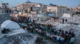 Di tengah gundukan puing dan reruntuhan bangunan yang hancur akibat gempa magnitudo 7,8, warga menikmati hidangan buka puasa Ramadhan bersama. (AFP/Aaref Watad)