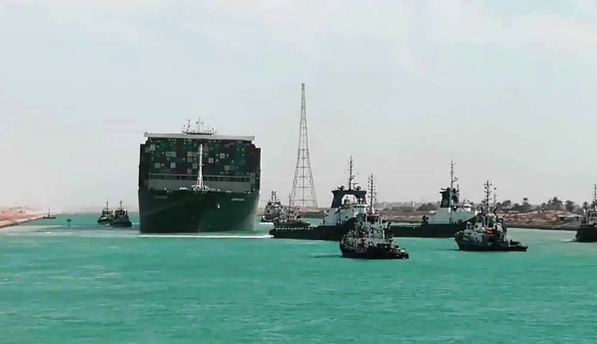Kapal kargo Ever Given ditemani kapal tunda saat melaju di Terusan Suez, Mesir, Senin (29/3/2021). Ratusan kapal sedang menunggu untuk melewati kanal yang menghubungkan Mediterania ke Laut Merah. (Suez Canal Authority via AP)