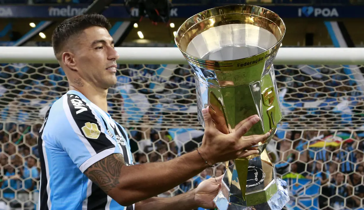 Pemain Gremio, Luis Suarez mengangkat trofi setelah memenangkan Gaucho Championship di Arena do Gremio Stadium, Porto Alegre, Brasil, 8 April 2023. Ini merupakan gelar kedua Suarez di Gremio setelah Recopa Gaucha yang dimenangkan pada 17 Januari 2023. (AFP/Silvio Avila)