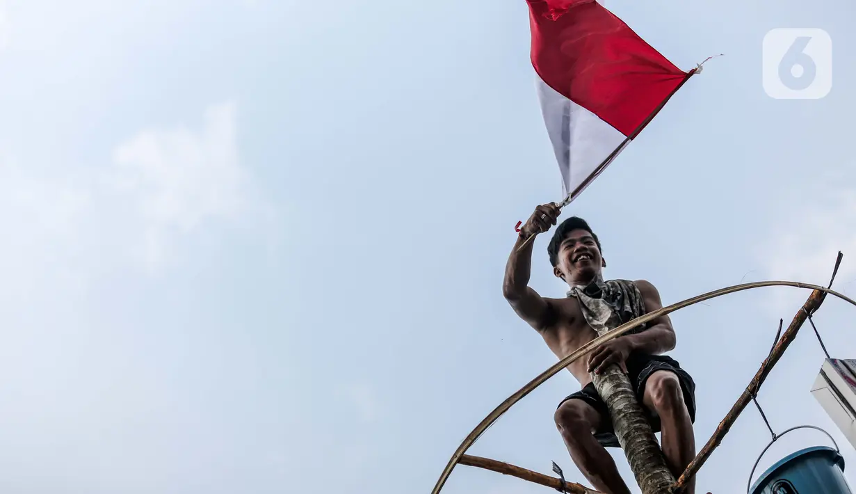 Peserta lomba panjat pohon pinang berhasil mencapai puncak di Pantai Festival Ancol, Jakarta, Rabu (17/8/2022). Sebanyak 45 pohon pinang siap dipanjat oleh pengunjung di Pantai Festival Ancol  untuk memeriahkan Hari Ulang Tahun (HUT) Ke-77 Republik Indonesia. (Liputan6.com/Faizal Fanani)
