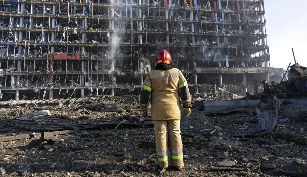Seorang petugas pemadam kebakaran melihat kerusakan setelah serangan sebuah pusat perbelanjaan di Kiev, Ukraina, Senin (21/3/2022). Delapan orang tewas dalam serangan tersebut. (AP Photo/Rodrigo Abd)