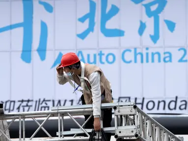 Seorang pekerja berada dekat papan bertuliskan "Hai Beijing, Auto China 2020" menjelang pameran Auto China 2020 yang akan digelar di Beijing, Kamis (24/9/2020). (AP Photo/Ng Han Guan)