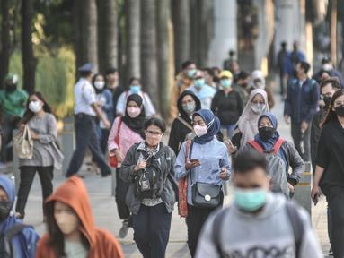 Pekerja melintas di trotoar Jalan Jenderal Sudirman saat jam pulang kantor, Selasa (4/1/2022). PPKM di Jakarta kembali diperpanjang oleh pemerintah pusat terhitung 4-17 Januari 2022 dari sebelumnya di Level 1 kini menjadi Level 2. (merdeka.com/Iqbal S. Nugroho)