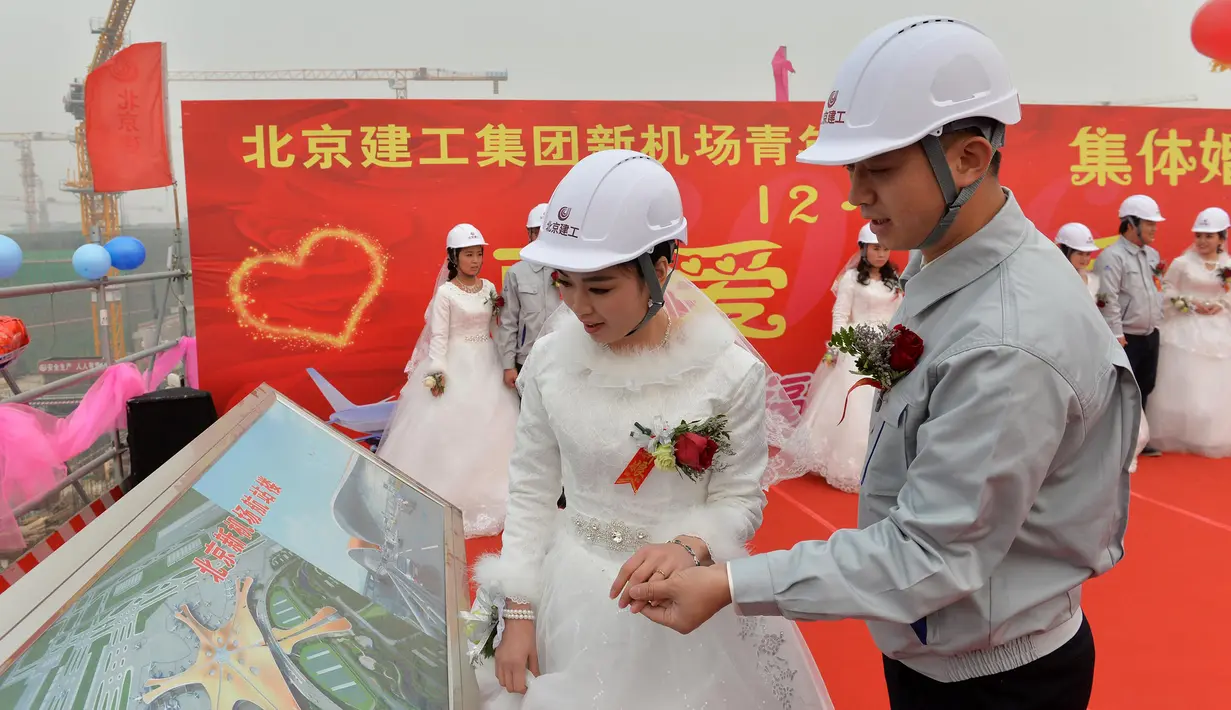 Pengantin pria memperlihatkan rancangan bandara pada pengantin wanitanya, Beijing, Senin (12/12). Kelima pekerja ini kompak untuk menggelar upacara pernikahan di tempat proyek mereka bekerja yaitu sebuah bandara. (AFP PHOTO)