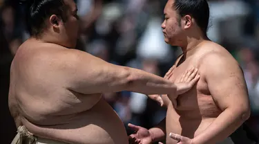 Para pegulat sumo melakukan pemanasan sebelum "turnamen sumo besar nazar", sebuah pameran sumo seremonial, di halaman Kuil Yasukuni di Tokyo pada 17 April 2023. (AFP/Philip Fong)