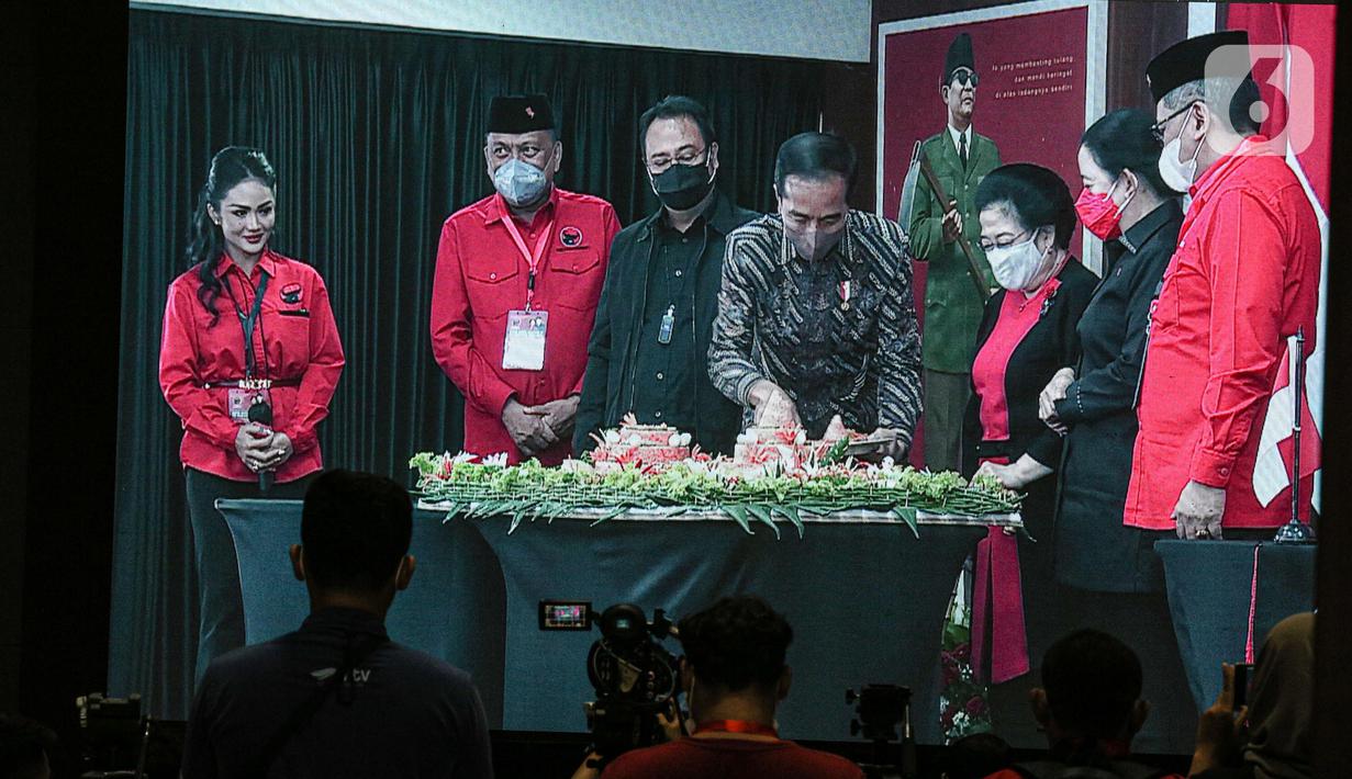 Presiden Joko Widodo atau Jokowi (tengah) memotong tumpeng disaksikan Ketua Umum PDIP Megawati Soekarnoputri (ketiga kanan) saat Rakernas II PDIP di Jakarta, Selasa (21/6/2022). Rakernas PDIP kali ini mengusung tema 'Desa Kuat, Indonesia Maju dan Berdaulat'. (Liputan6.com/Faizal Fanani)