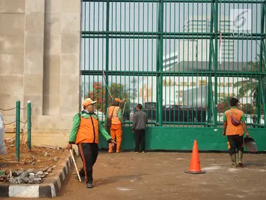 Petugas membersihkan sampah sisa bentrok antara mahasiswa dan polisi dalam unjuk rasa di depan Gedung DPR RI, Jakarta, Rabu (25/9/2019). Bentrokan pada Selasa (24/9/2019) menyisakan sampah yang memenuhi kawasan di sekitar Gedung DPR. (Liputan6.com/Immanuel Antonius)