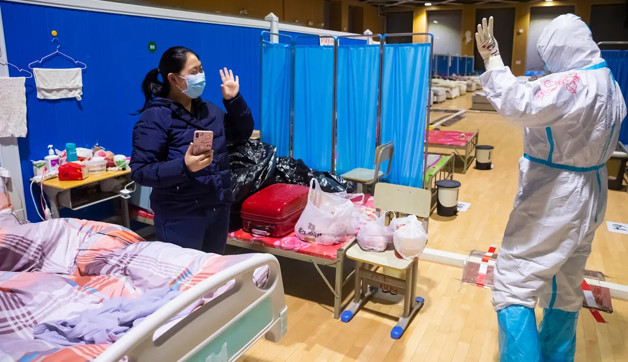 Pasien virus corona atau COVID-19 Ying (kiri) melambaikan tangan kepada petugas medis Cao Jinglei di sebuah rumah sakit sementara di Wuhan, China, Senin (9/3/2020). China menutup semua rumah sakit sementara yang dibuat untuk menangani virus corona di Kota Wuhan. (Xinhua/Shen Bohan)