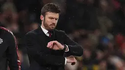 Hal itu disampaikan MU di laman resmi klub pada Rabu (14/1/2026) dini hari WIB. Tampak dalam foto, Michael Carrick saat masih menjadi pelatih sementara Manchester United melihat arlojinya selama pertandingan sepak bola Liga Premier Inggris melawan Arsenal di Old Trafford, Manchester, Inggris barat laut, pada 2 Desember 2021. (Oli SCARFF/AFP)