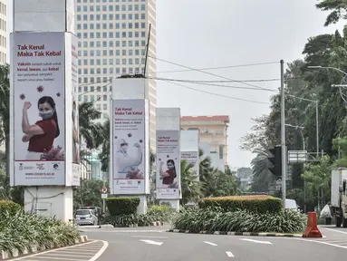 Kendaraan melintas di dekat papan reklame sosialisasi vaksin Covid-19 di tiang pancang proyek monorel, Senayan, Jakarta, Selasa (17/11/2020). Tiang pancang monorel yang terbengkalai selama 16 tahun itu dimanfaatkan oleh sebagai papan reklame sosialisasi vaksin Covid-19. (merdeka.com/Iqbal S Nugroho)
