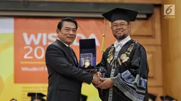 Rektor Universitas Terbuka Drs. Ojat Darojat, M.Bus., Ph.D memberikan cinderamata kepada Kepala Staf Kepresidenan Moeldoko usai memberikan orasi ilmiah saat wisuda Universitas Terbuka, Tangerang Selatan, Selasa (3/7). (Liputan6.com/Faizal Fanani)