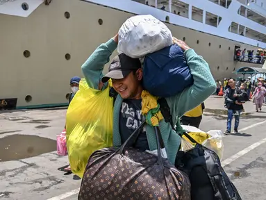 Seorang penumpang membawa barang-barangnya setelah turun dari kapal di pelabuhan Perak di Surabaya pada 3 April 2024. (JUNI KRISWANTO/AFP)