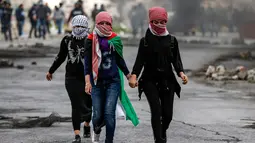 Wanita Palestina berjalan selama bentrokan dengan tentara Israel dalam demonstrasi untuk memperingati Hari Tanah di Tepi Barat, Sabtu (30/3).(Photo by ABBAS MOMANI/AFP)