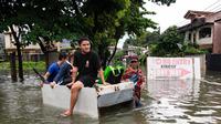 Orang-orang menaiki rakit darurat melewati jalan yang tergenang banjir di sebuah desa di Cainta Town, sebelah timur Manila pada 22 Juli 2025, setelah hujan monsun. (Ted ALJIBE/AFP)