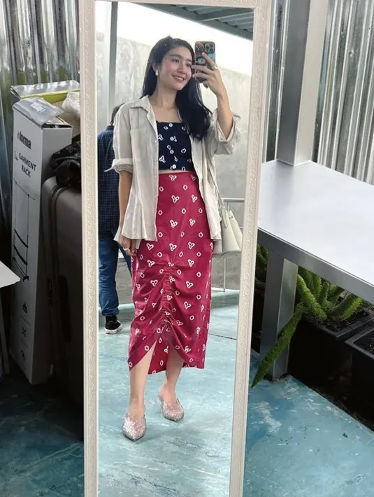 Ia juga tampil dengan kain motif jumputan yang dijadikan crop top hitam dan skirt merah, yang dipadukan outer kemejanya. [Instagram/@febbyrastanty]