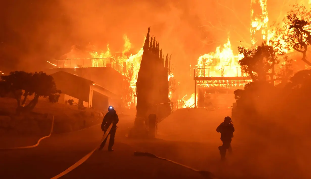 Petugas memadamkan api di sebuah rumah di Ventura, California, AS (5/12). Sekitar penghuni 7.786 rumah di Ventura dan Santa Paula mendapat mandat evakuasi wajib dari dinas pemadam kebakaran lokal. (Ryan Cullom / Ventura County Fire Department via AP)