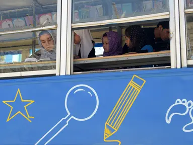 Anak-anak Afghanistan membaca buku dalam bus yang dijadikan perpustakaan keliling di Kabul, 4 April 2018. Charmaghz, nama bus keliling tersebut yang dalam bahasa setempat berarti 'kacang kenari', karena bentuknya menyerupai otak manusia. (AFP/Shah MARAI)