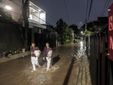 Warga melewati rumah yang tergenang banjir di jalan Bank, Jakarta Selatan, Selasa (4/10/2022). Hujan yang mengguyur wilayah Ibu Kota Jakarta mengakibatkan banjir menggenangi kawasan Kemang, Jakarta. (Liputan6.com/Johan Tallo)