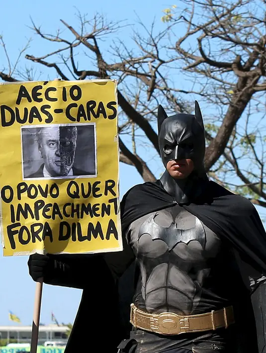 Aktivis mengenakan kostum Batman membawa tulisan berisi protes kepada Presiden Brasil Dilma Rousseff di Gedung Kongres Nasional, Brasil (27/5/2015). Tuntutan ini didasari banyaknya kasus korupsi yang menjerat Presiden Dilma. (REUTERS/Adriano Machado)