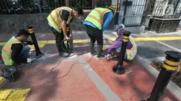 Pekerja memasang Bolar atau tiang pembatas pedestrian di kawasan Tugu Tani, Jakarta, Minggu (9/9). Pemasangan Bolar bertujuan menjaga keindahan jalur pedestrian dan mencegah penyalahgunaan fungsi.(merdeka.com/ Iqbal S. Nugroho)